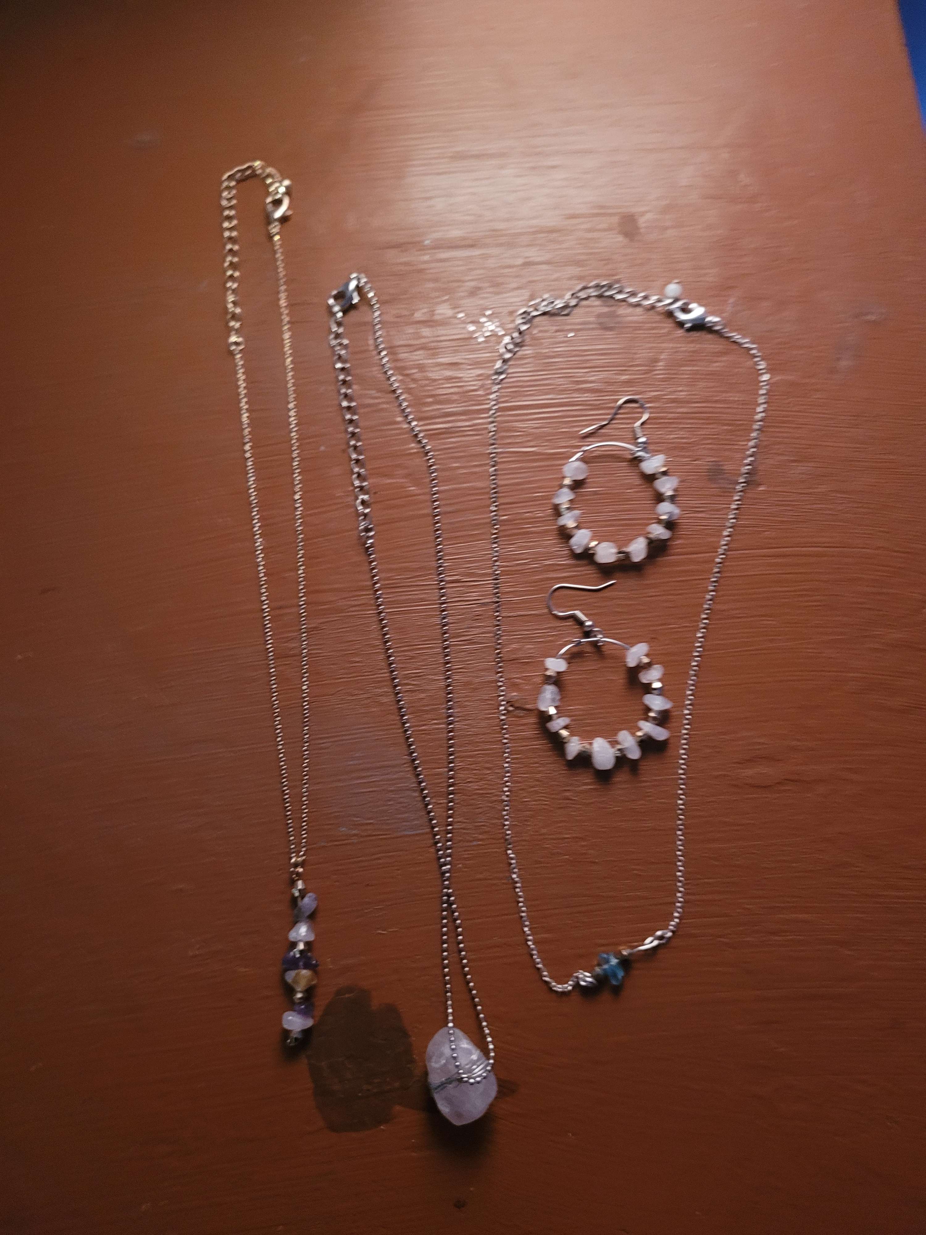 Two simple necklaces, and a pair of earrings on a table.