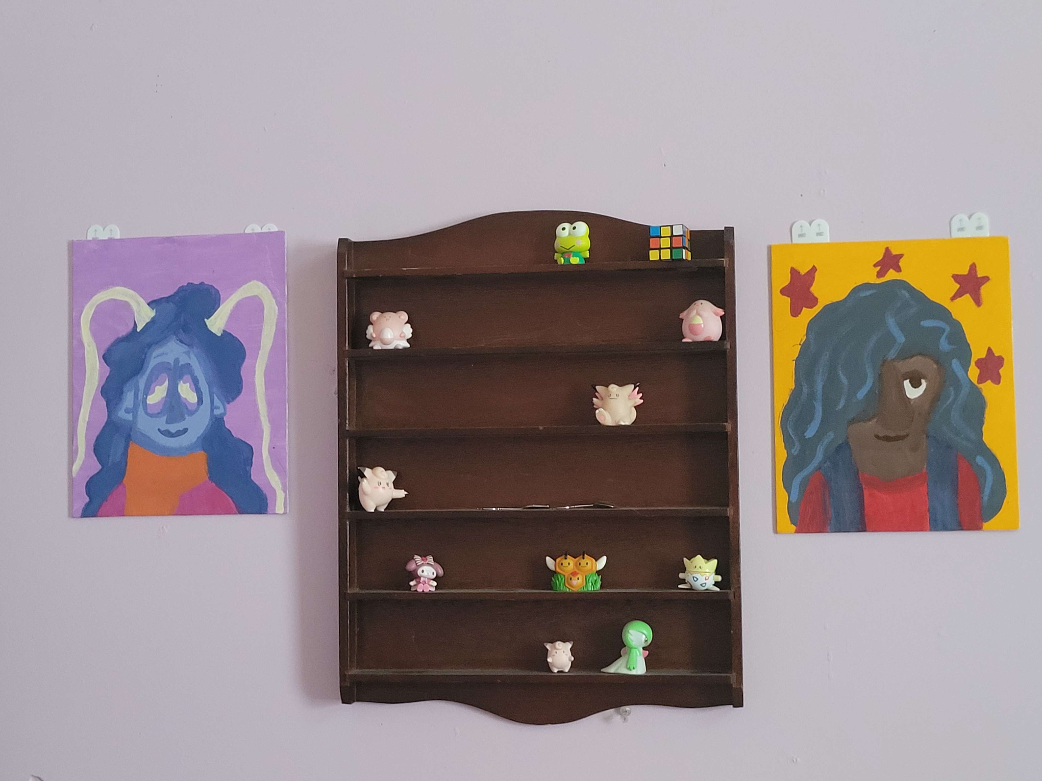 Two paintings, an alien with blue skin and hair, and a woman with black hair covering one eye.