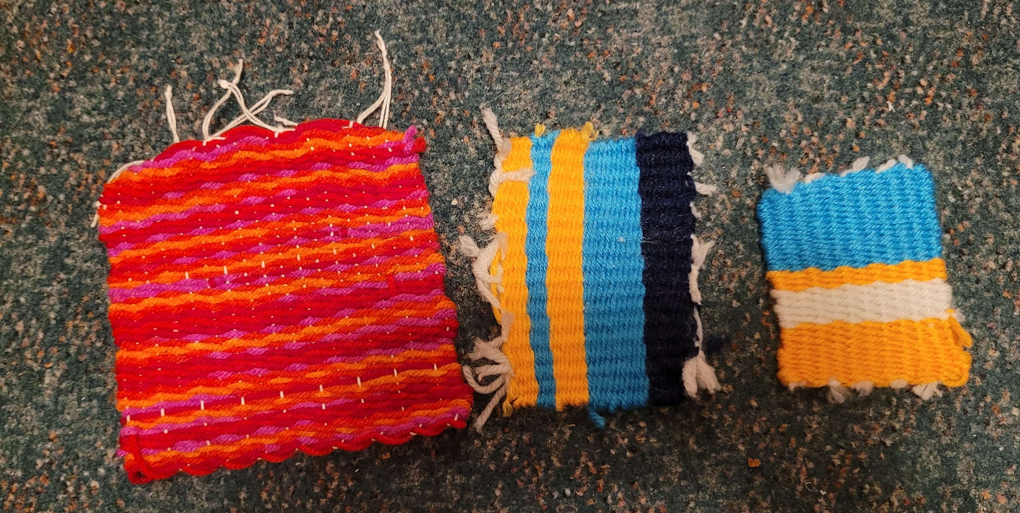 Three small woven squares, one is pink, the other two are yellow, blue and white