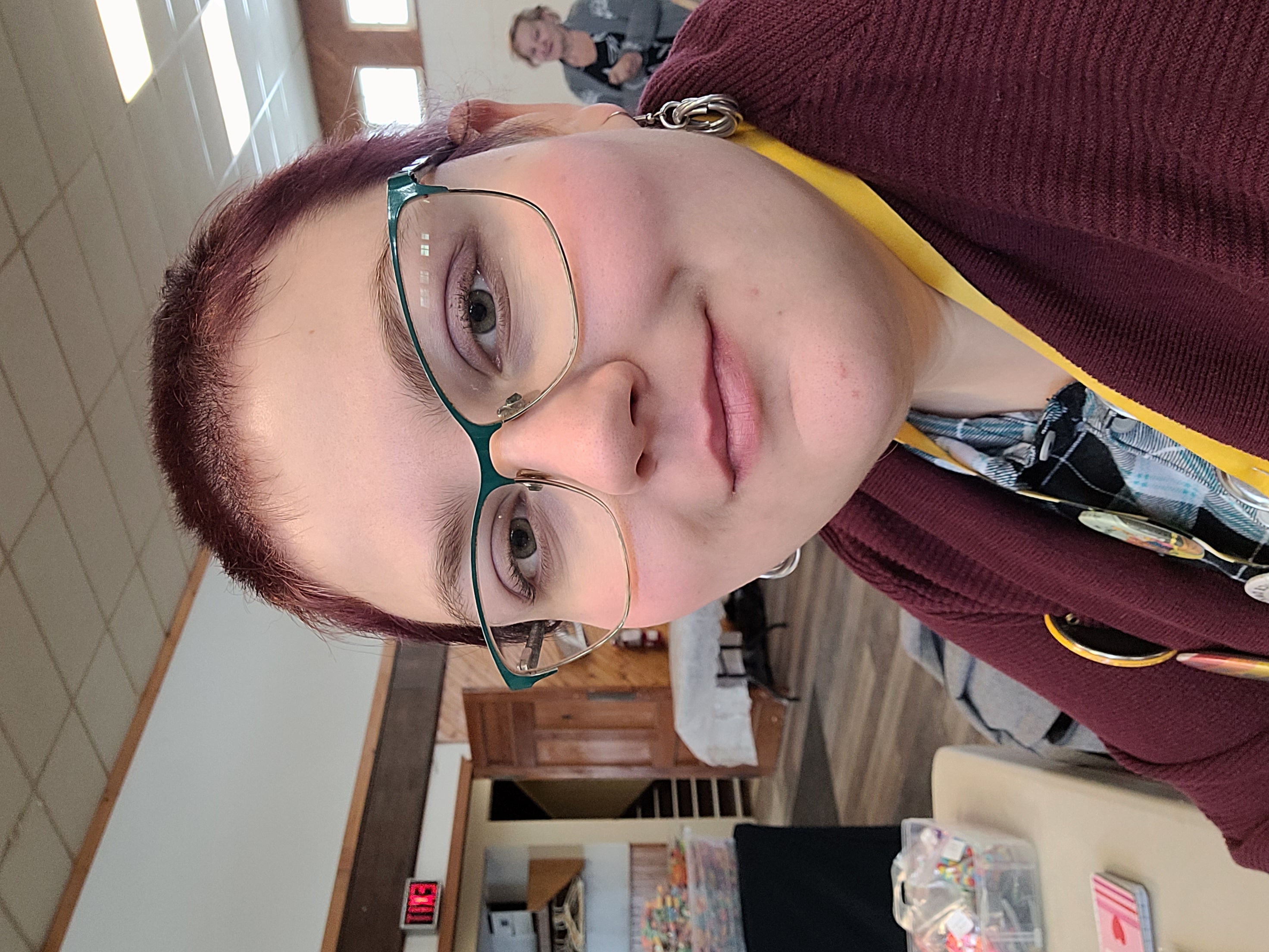 A selfie of Emilie, the buisness creator, she has a purple buzzcut and glasses.